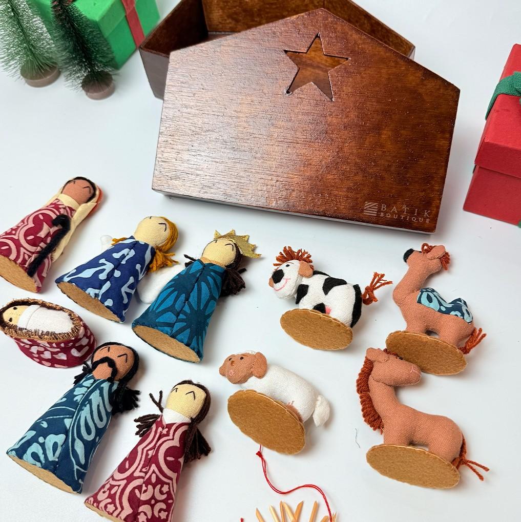 Set of nativity scene figurines with a wooden stable and gift boxes on a white background.