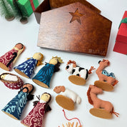 Set of nativity scene figurines with a wooden stable and gift boxes on a white background.