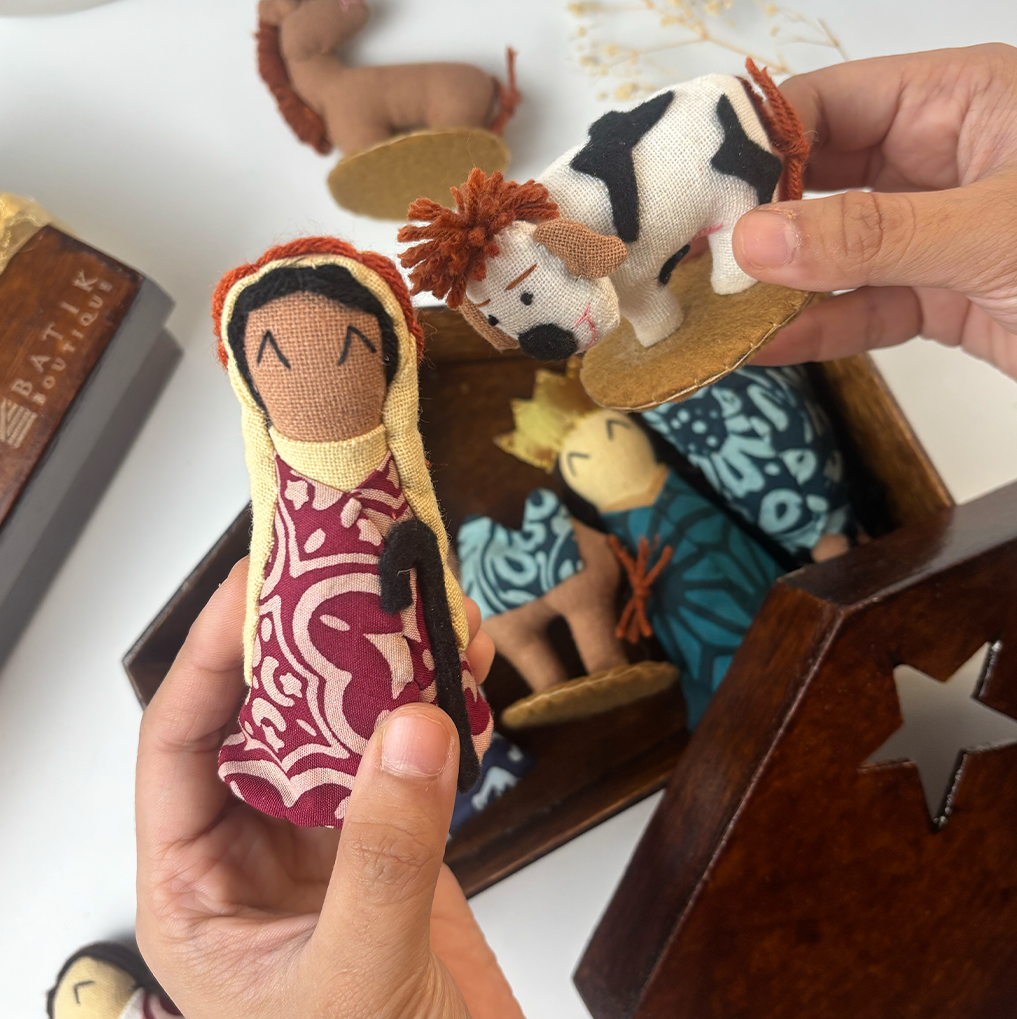 Hand holding a nativity scene figurine with other figures in the background