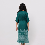 Girl wearing a green dress with a white pattern on a plain background