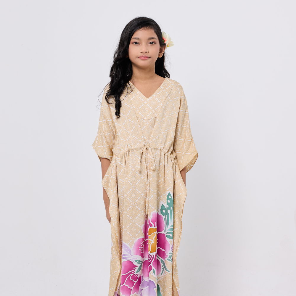 Woman wearing a beige dress with floral designs on a white background