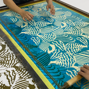 Screen printing process with a person using a squeegee on a screen with shell designs.