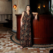 Woman in a patterned dress standing in an elegant interior setting.