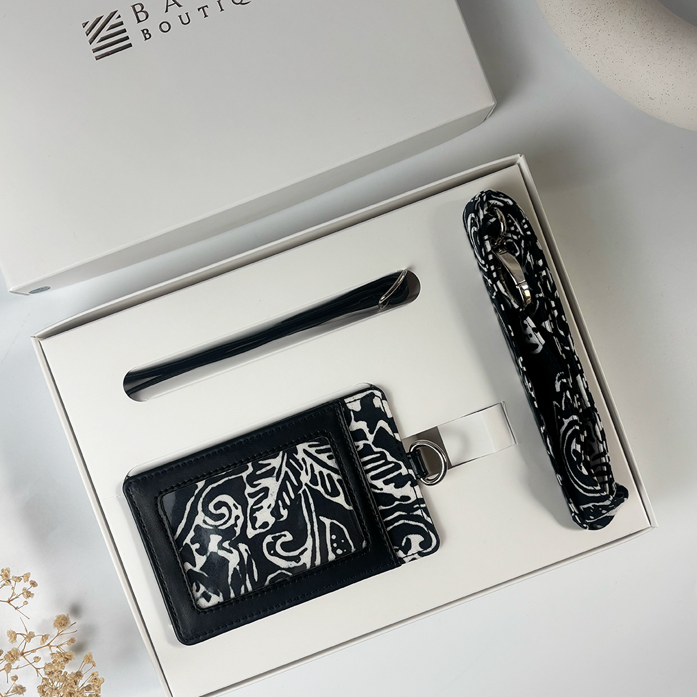 Set of black and white patterned items including a cardholder, pen, and strap in a box with 'Boutiq' branding.
