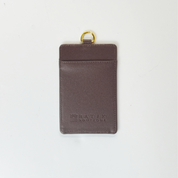 Brown leather cardholder with gold ring on a white background
