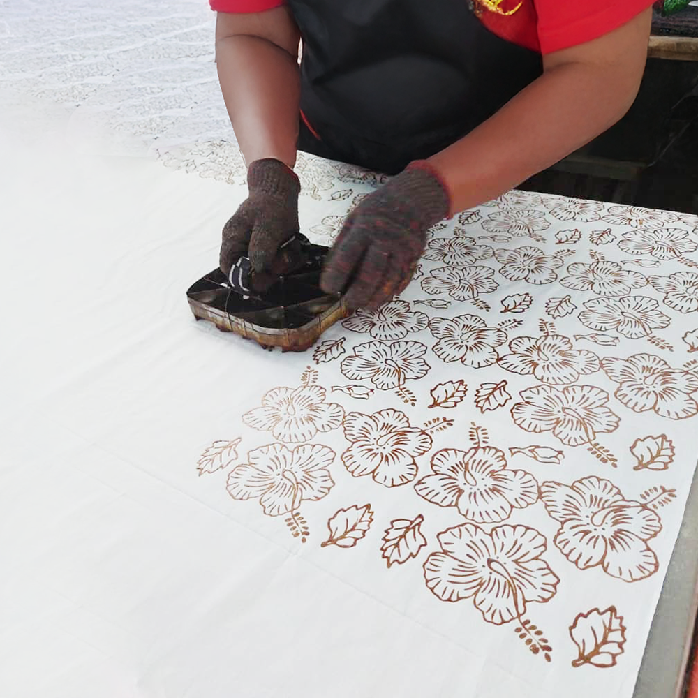 Person applying a floral design to a surface using a stamp.
