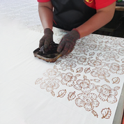 Person applying a floral design to a surface using a stamp.