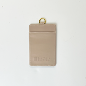 Beige cardholder with gold ring on a white background