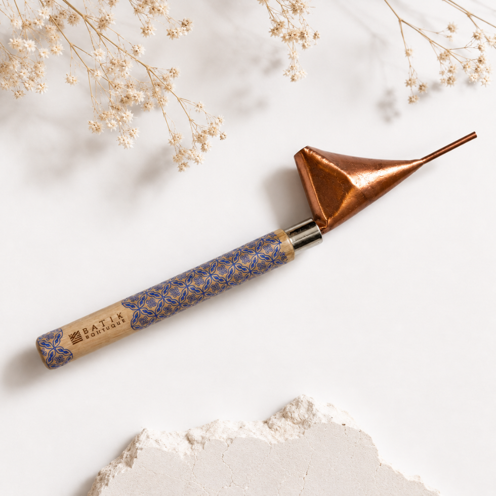 A handcrafted metal and wood tool with a copper-colored conical head, a silver collar, and a patterned blue and gold handle, styled on a white background with dried flowers and a stone slice.