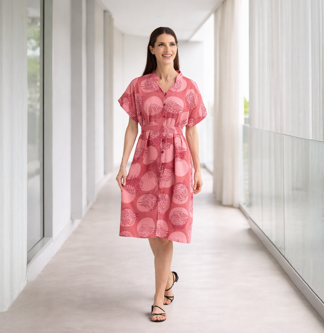 Woman wearing a pink dress with a pattern in a modern indoor setting