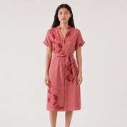 Woman wearing a batik pink dress with floral patterns on a white background