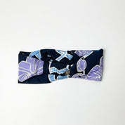 Navy blue headband with purple and white floral pattern on a light gray background