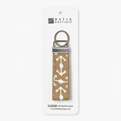 A Batik Boutique keychain with a tan and white batik patterned fabric strap and silver metal hardware, displayed on its white retail card.