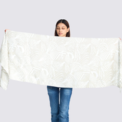 Woman holding a grey printed batik scarf to show the sizing, color and design of the scarf