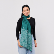 Woman wearing a green scarf with a white pattern on a plain background