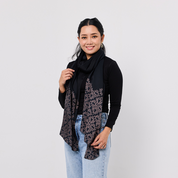 Woman wearing a black scarf with a patterned end against a plain background