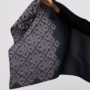 Black and patterned scarf being held against a light gray background