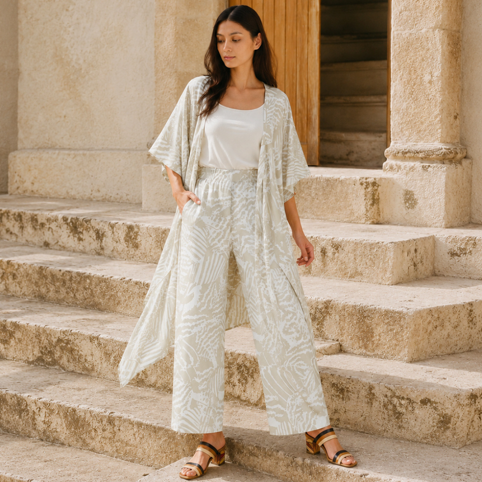 Woman wearing grey printed wide leg trousers along with the same printed kimono posing by stairs