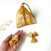 Yellow patterned bag with a hand holding two yellow patterned items on a white background