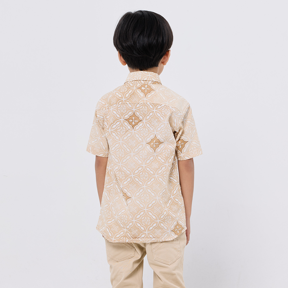 Child wearing a beige patterned shirt and pants on a white background