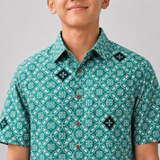 Person wearing a green patterned shirt against a gray background