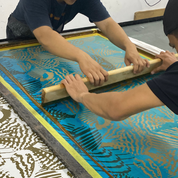 Screen printing process with a person using a squeegee on a screen with shell designs.