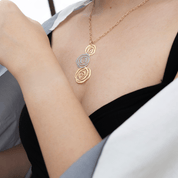 Gold and silver necklace worn by a person with a neutral background