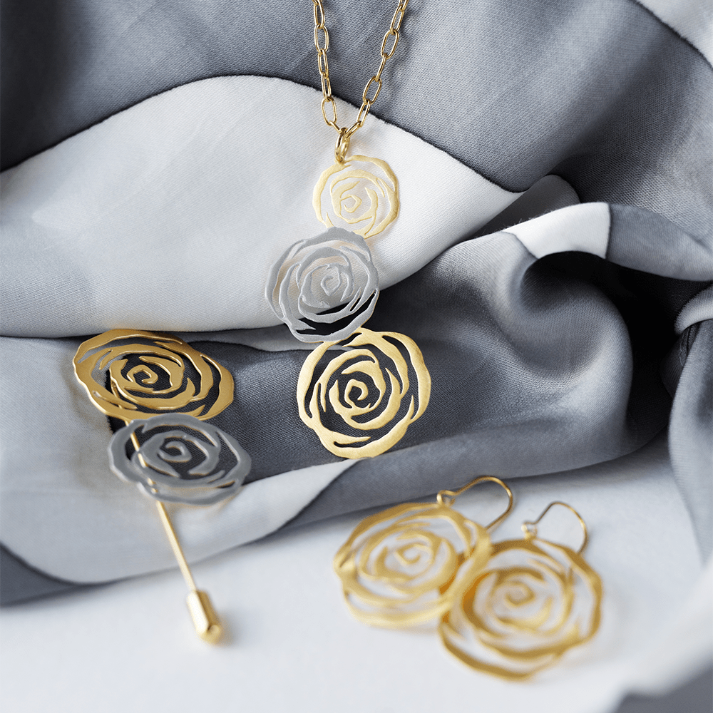 Gold and silver rose-shaped jewelry set on gray fabric
