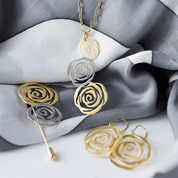 Gold and silver rose-shaped jewelry set on gray fabric