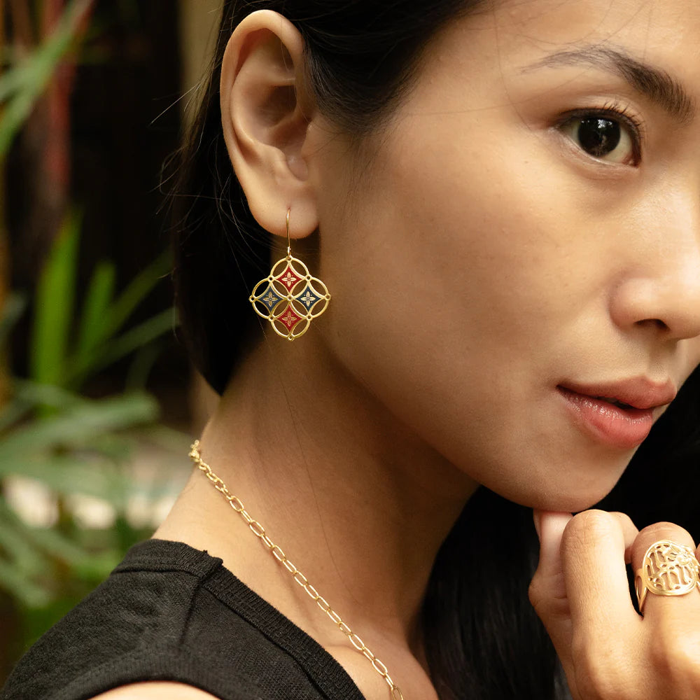 Close-up of a woman wearing gold earrings, necklace, and ring with a blurred green background