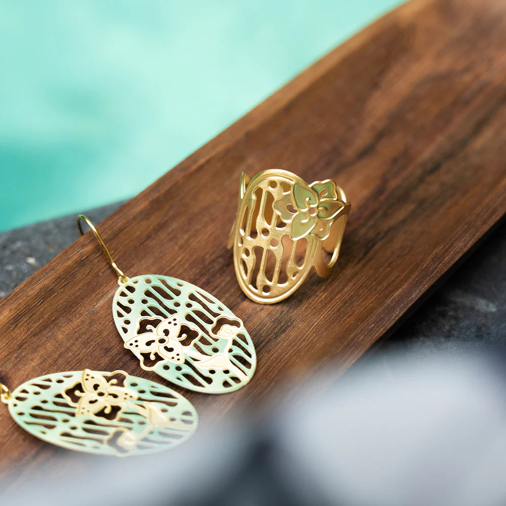 Gold earrings and ring on a wooden surface with a blurred background