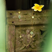 Gold necklace with floral design on a wooden surface with a yellow flower.