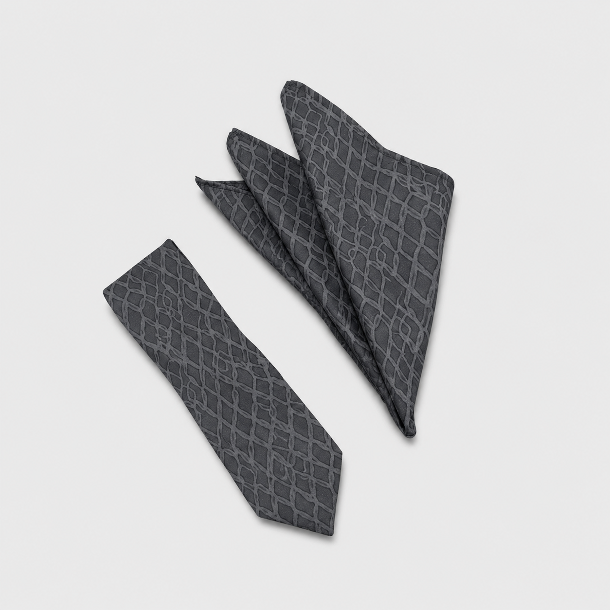 A dark gray necktie and matching pocket square set with a subtle snakeskin pattern, displayed on a light gray background.