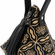 Close-up of a black handbag with a tan floral and paisley pattern, black leather handles, a black leather tassel zipper pull, and a silver-tone metal brand plaque reading 'MATIX BOUTIQUE'.