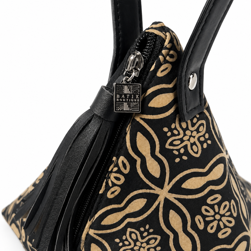Close-up of a black handbag with a tan floral and paisley pattern, black leather handles, a black leather tassel zipper pull, and a silver-tone metal brand plaque reading 'MATIX BOUTIQUE'.