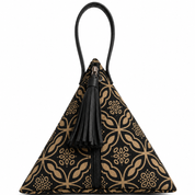 A small pyramid-shaped handbag with a black and tan floral pattern, featuring a black leather top handle, a black leather tassel charm, and a black front zipper, shown against a plain white background.