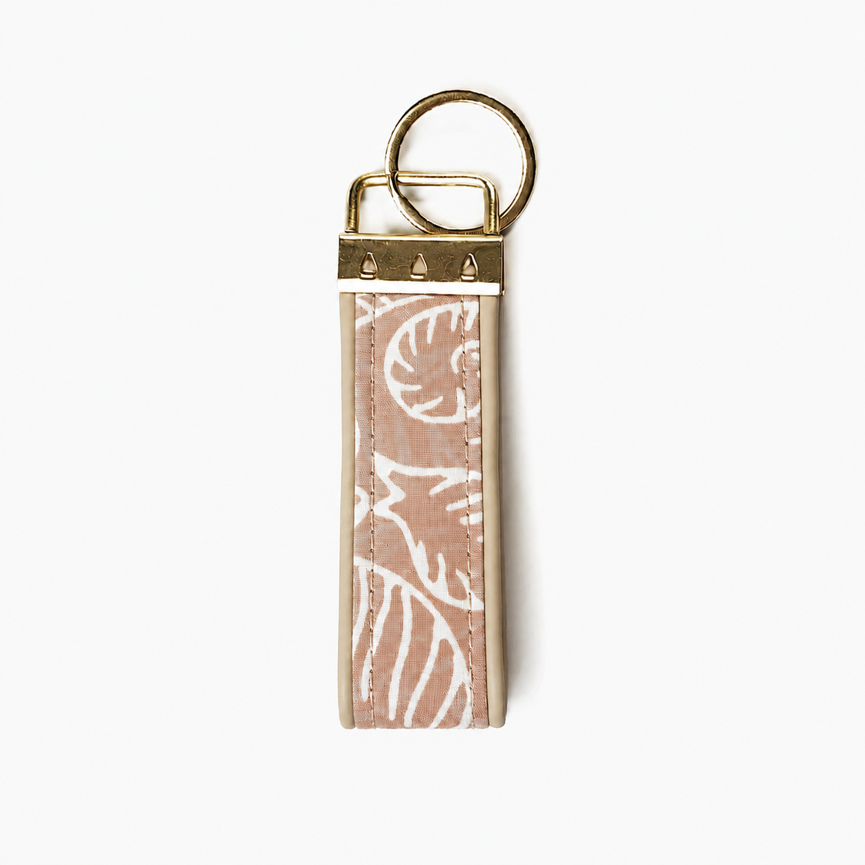 A rectangular keychain or key tag with a dusty pink and white patterned strap, finished with brass-toned metal hardware and a split key ring, shown on a plain white background. Showing the back