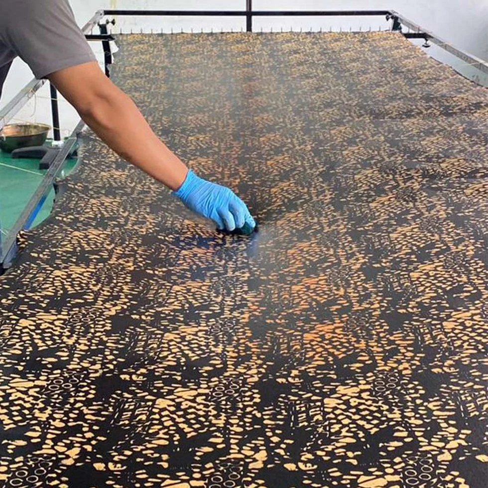 Person applying a patterned material to a large surface with gloves on