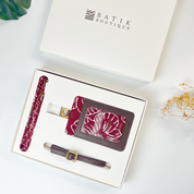Set of travel accessories including a pen, luggage tag, and belt with maroon and gray design in a Batik Boutique box.