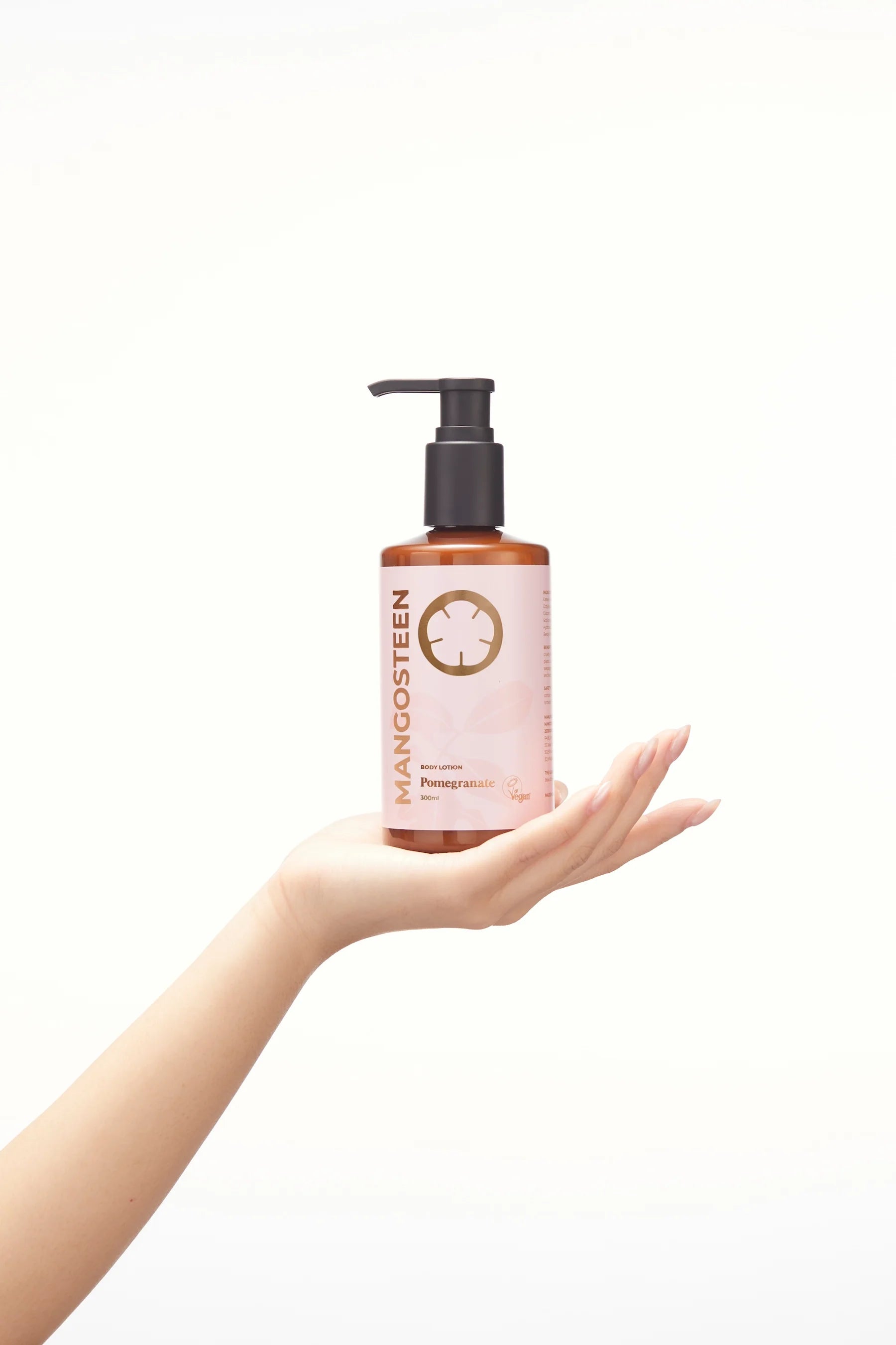 Hand holding a pink bottle labeled 'Mangosteen' against a white background