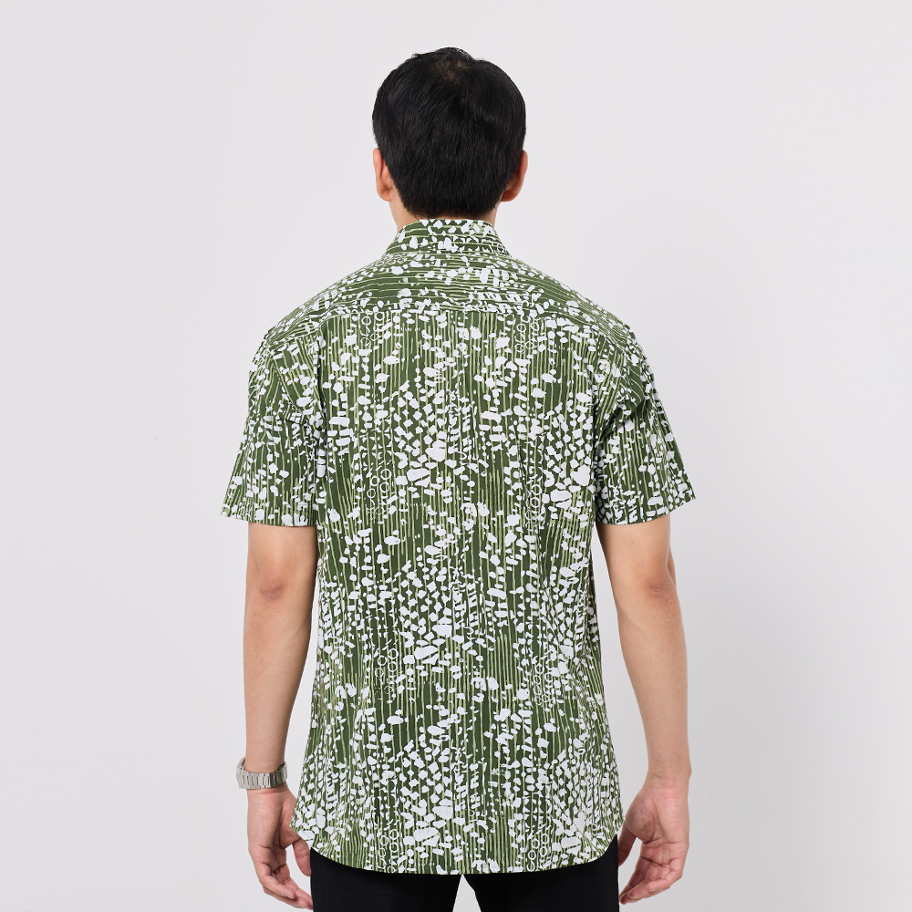 Person wearing a green and white patterned shirt on a plain background