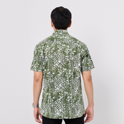 Person wearing a green and white patterned shirt on a plain background