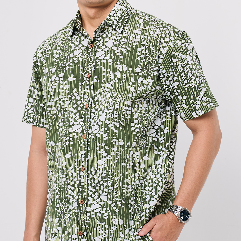 Person wearing a green and white patterned shirt on a plain background