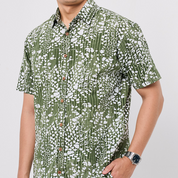 Person wearing a green and white patterned shirt on a plain background
