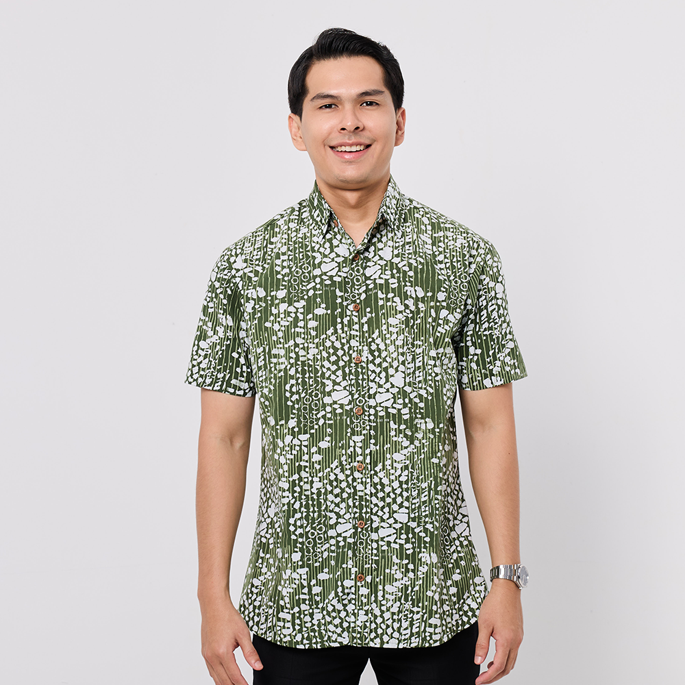 Man wearing a green and white patterned shirt on a gray background