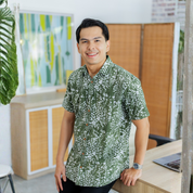 Man wearing a green patterned batik shirt in an office setting