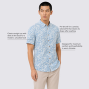 A man modeling a light blue and white patterned short-sleeve button-up shirt with beige pants, set against a light gray background with three text callouts describing the shirt's features.