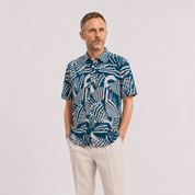 A man wearing a blue button-up shirt with a blue shell pattern, on a white background.