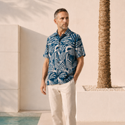Man Posing in Blue Printed Button Up with a resort background