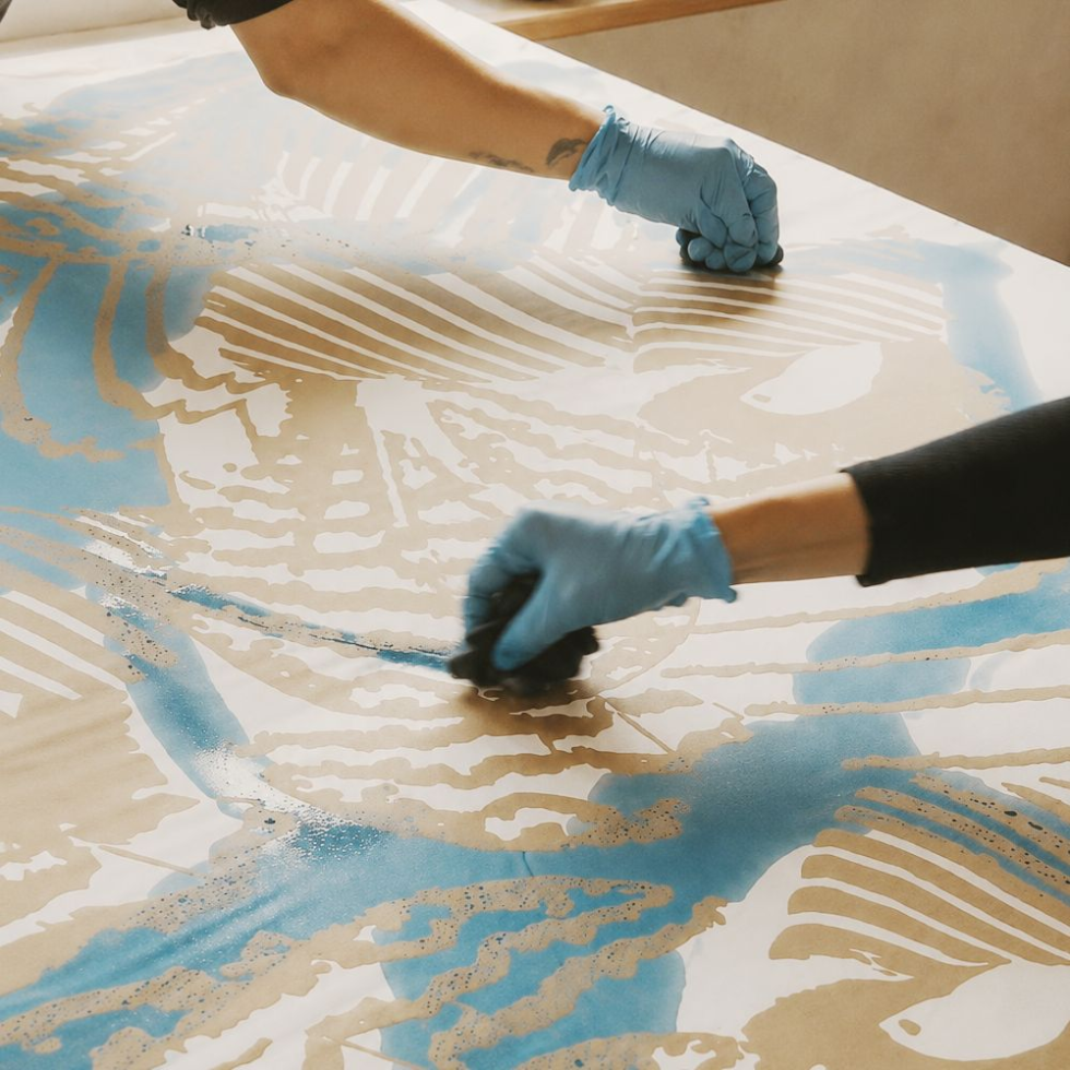 Person wearing blue gloves applying a blue substance to a textured surface